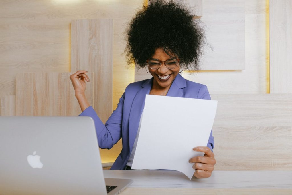 Employee celebrating at her desk while reading a document
