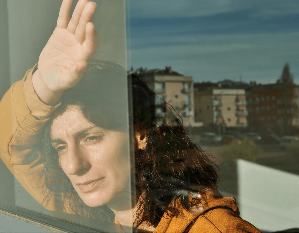 Woman waving through a window, illustrating the distance between members of a virtual team