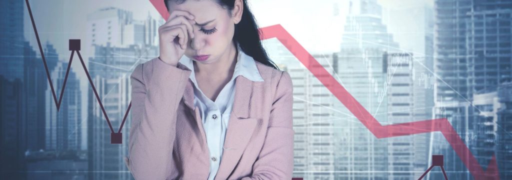 Employee with head in hands against a falling graph, illustrating culture deteriorating since the pandemic