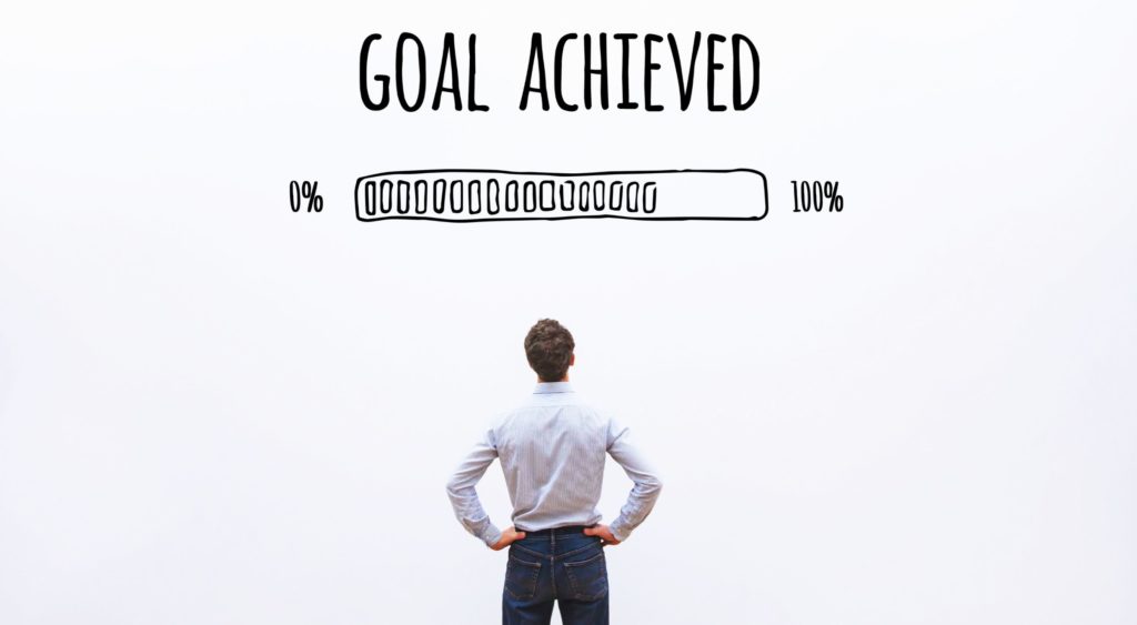 Man facing a progress bar approaching 100% under the words goal achieved