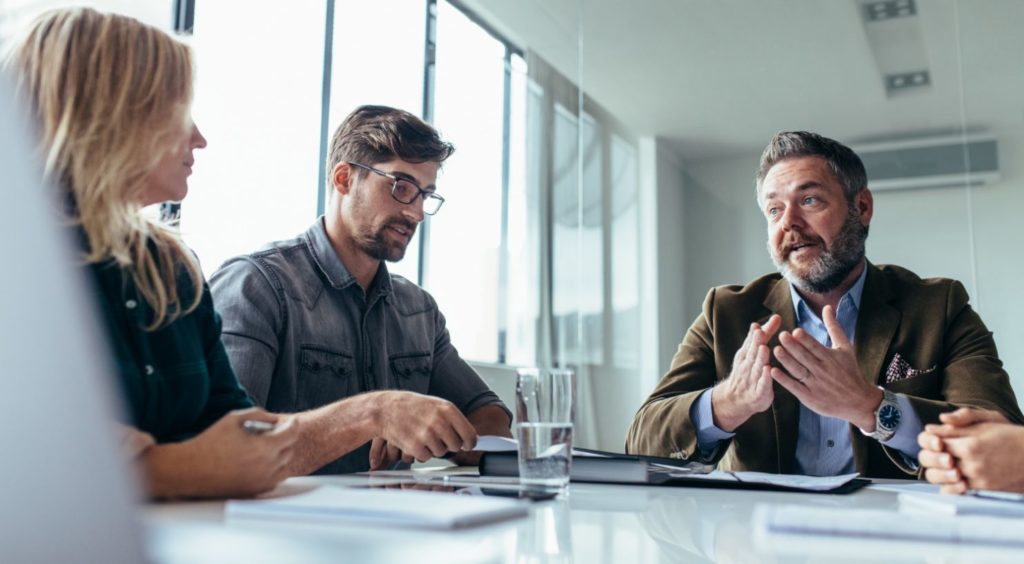 Managers in a meeting discussing feedback, illustrating continuous review conversations
