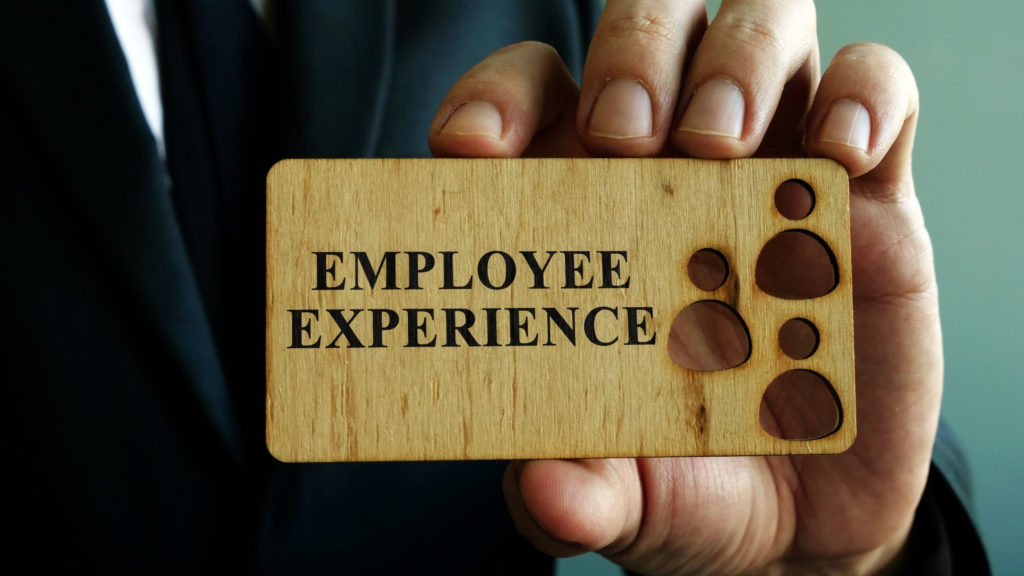 Hand holding a wooden card engraved with the words employee experience