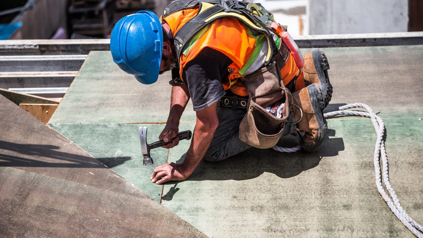 A construction worker in a hard hat and hi-vis working on a site, one of the frontline roles where feedback is rarely recorded
