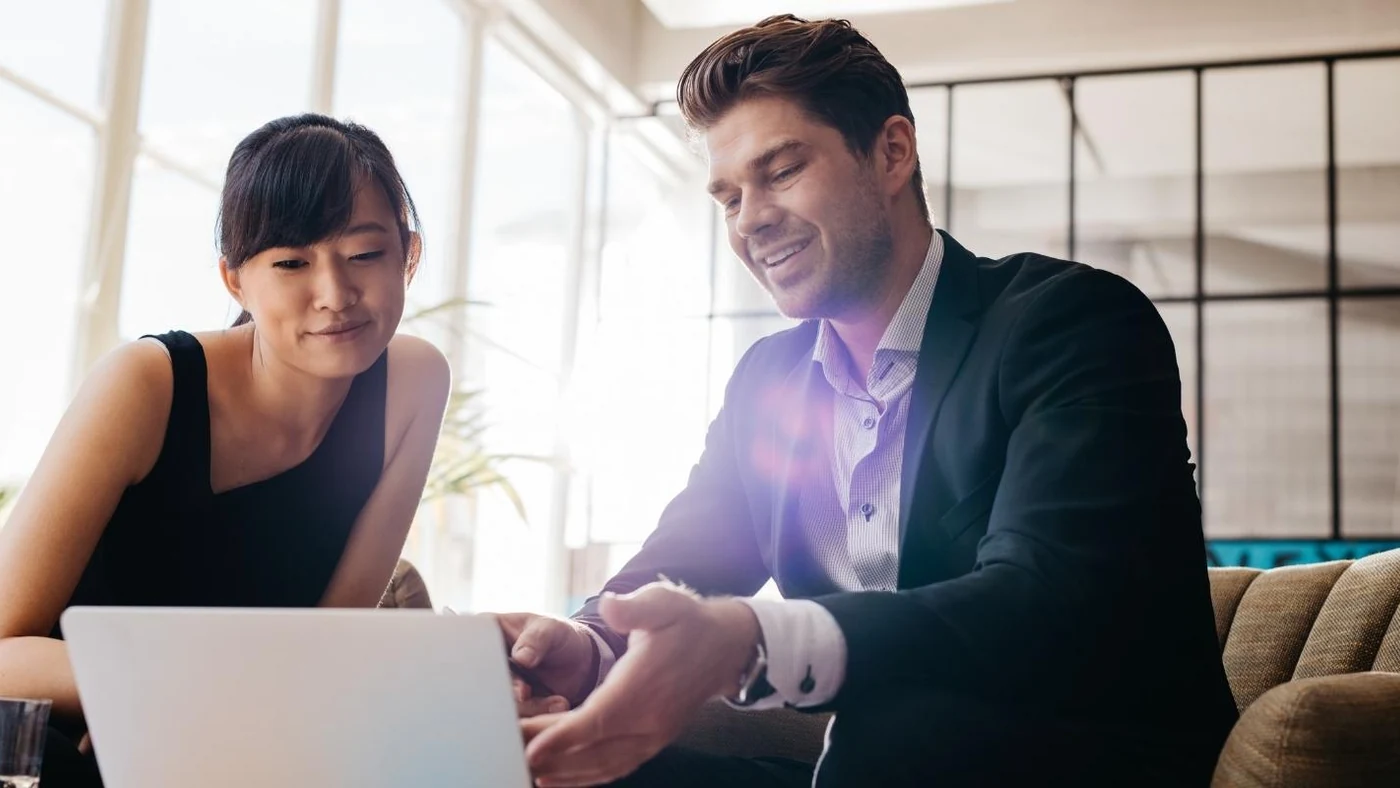 An HR business partner and a manager side by side at a laptop reviewing one-to-one and check-in data together