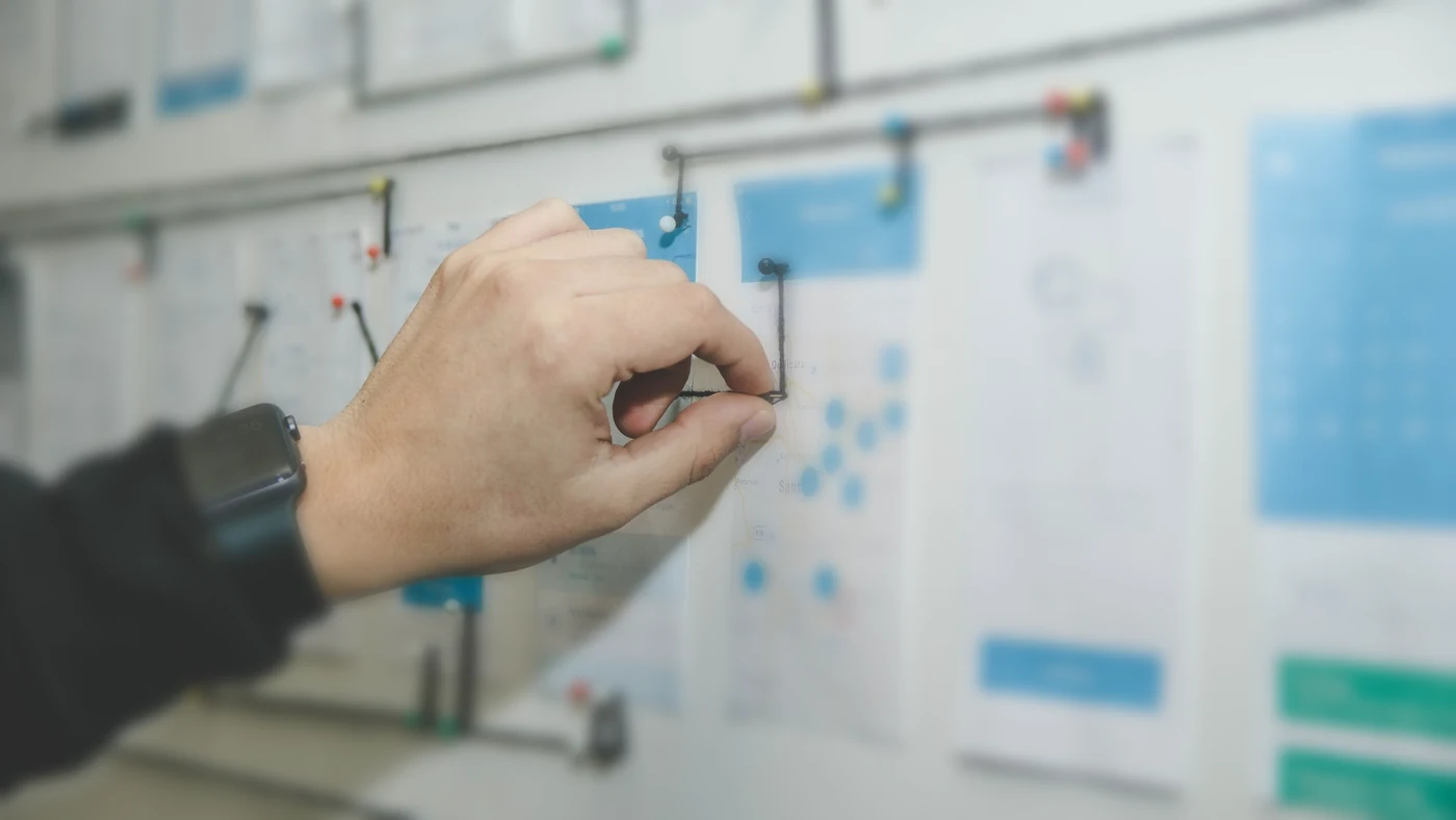 A person pinning a connection between cards on a process mapping wall