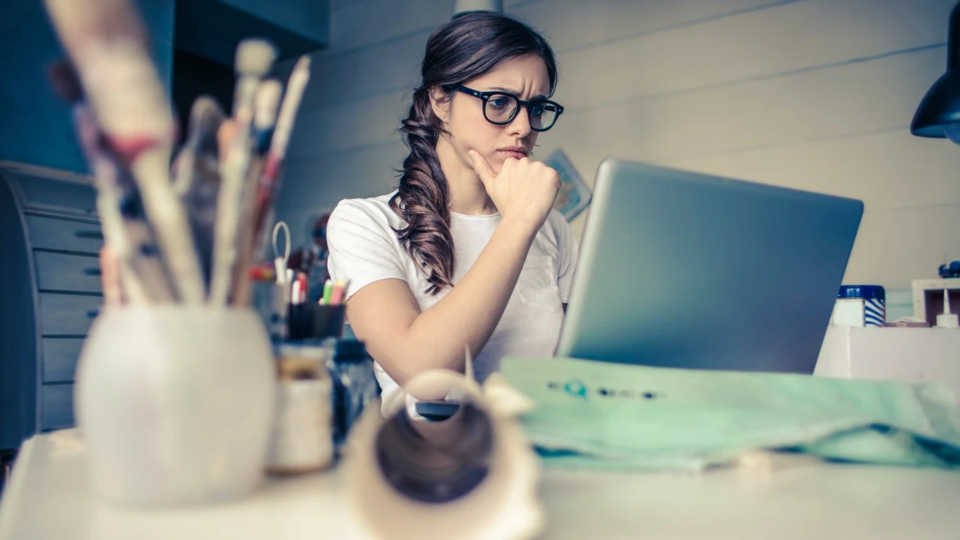 An employee sitting alone at a desk looking anxiously at a laptop, one of the quieter signs of disengagement